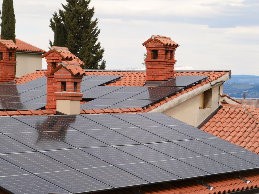 Roof-mounted solar panels on a shingled home with winter snow, visible flashing, and clear access pathways.